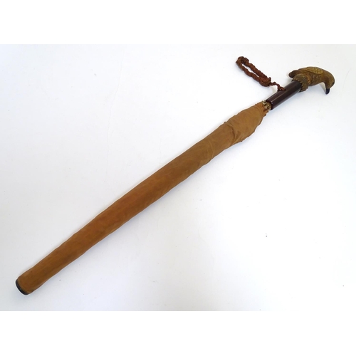 199 - A mid 20thC umbrella with Bakelite handle surmounted by carved figure of a bird. Approx 25'' long