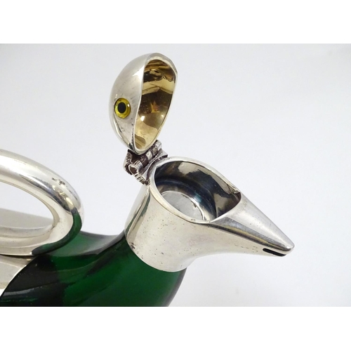 225 - A 21stC novelty claret jug / water jug of stylised duck form between glass body and silver plate mou... 