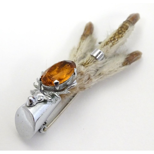 327 - A grouse foot brooch with silver plated mounts and amber coloured stone and stag decoration. marked ... 