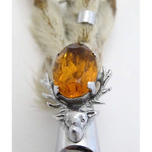 327 - A grouse foot brooch with silver plated mounts and amber coloured stone and stag decoration. marked ... 