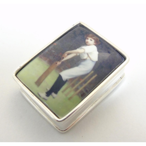 444 - A pill box with enamel decoration to top depicting a young boy playing cricket, approx 1 1/4'' x 1''... 