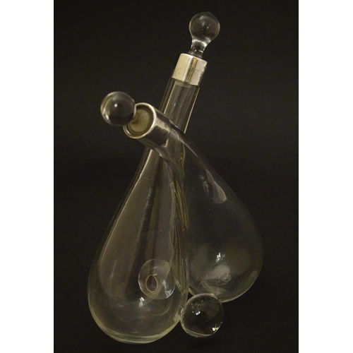 108 - Cross oil and vinegar bottles: a glass pair of oil and vinegar bottles of crossed form, silver mount... 