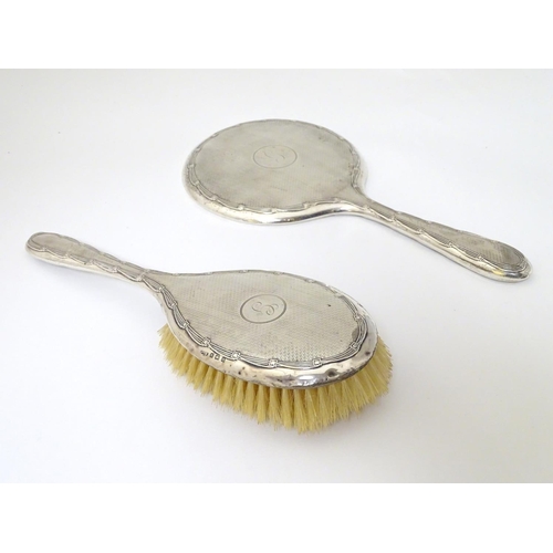 126 - A silver backed hand mirror and brush with engine turned decoration. Hallmarked Birmingham 1911/12  ... 