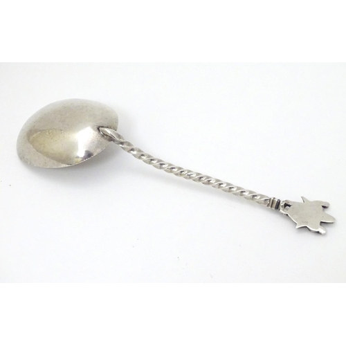 142 - A white metal spoon with engraved bowl and twist handle surmounted by a deity / Buddha. 5 3/4'' long