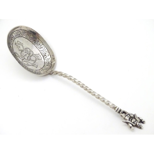 142 - A white metal spoon with engraved bowl and twist handle surmounted by a deity / Buddha. 5 3/4'' long