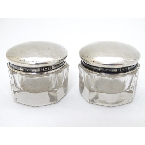 150 - A pair of glass pots with silver tops hallmarked Birmingham 1918 maker G & C Ltd. 1 1/4'' wide