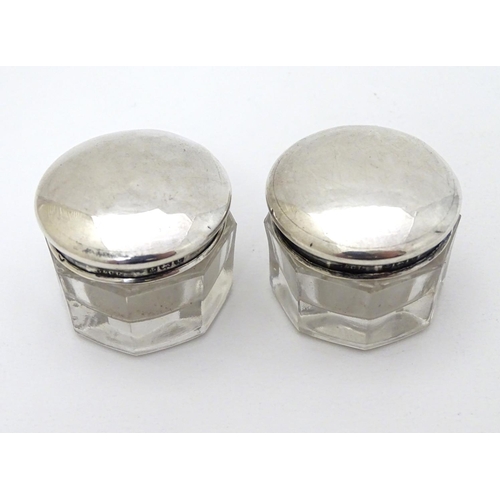 150 - A pair of glass pots with silver tops hallmarked Birmingham 1918 maker G & C Ltd. 1 1/4'' wide