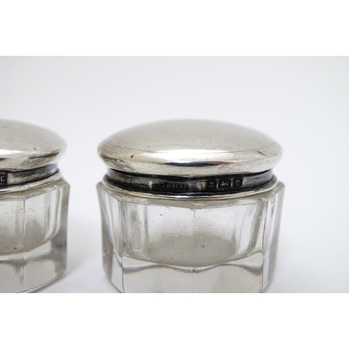 150 - A pair of glass pots with silver tops hallmarked Birmingham 1918 maker G & C Ltd. 1 1/4'' wide