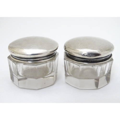 150 - A pair of glass pots with silver tops hallmarked Birmingham 1918 maker G & C Ltd. 1 1/4'' wide