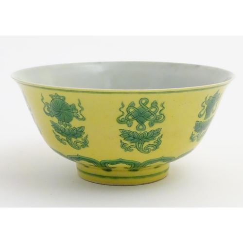 18 - A Chinese bowl decorated with green auspicious motifs above scrolling lotus flowers on a yellow grou... 