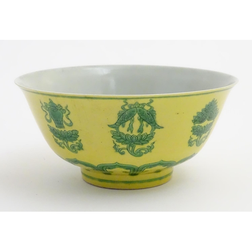 18 - A Chinese bowl decorated with green auspicious motifs above scrolling lotus flowers on a yellow grou... 