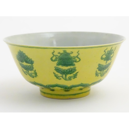 18 - A Chinese bowl decorated with green auspicious motifs above scrolling lotus flowers on a yellow grou... 