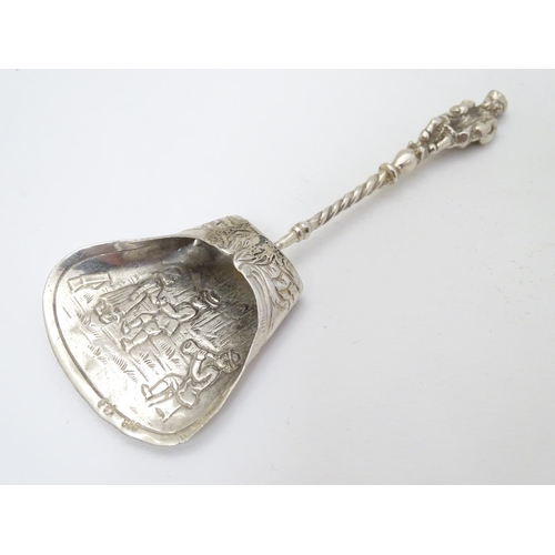 205 - A Continental white metal caddy spoon depicting figures dancing. German . 800 silver 4'' long