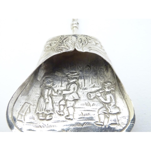 205 - A Continental white metal caddy spoon depicting figures dancing. German . 800 silver 4'' long