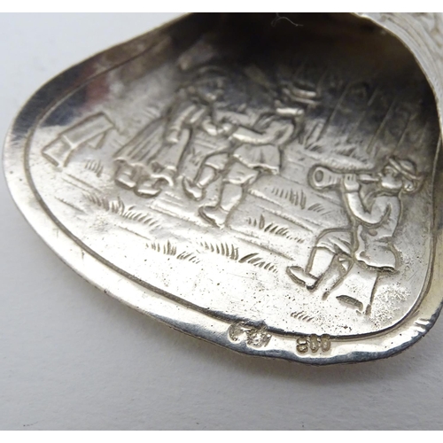 205 - A Continental white metal caddy spoon depicting figures dancing. German . 800 silver 4'' long