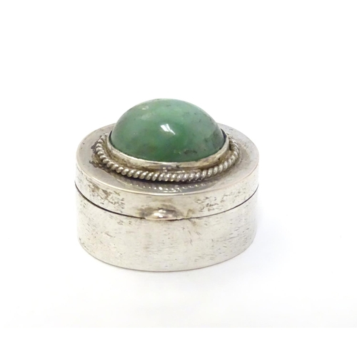 216 - A white metal pill box of oval form with jade cabochon to lid. 1'' wide