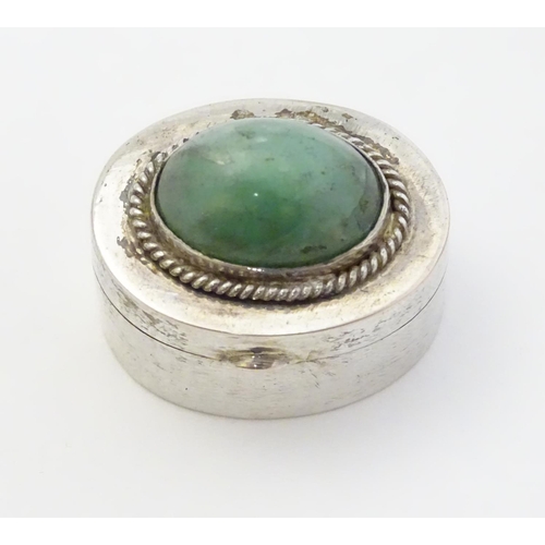 216 - A white metal pill box of oval form with jade cabochon to lid. 1'' wide