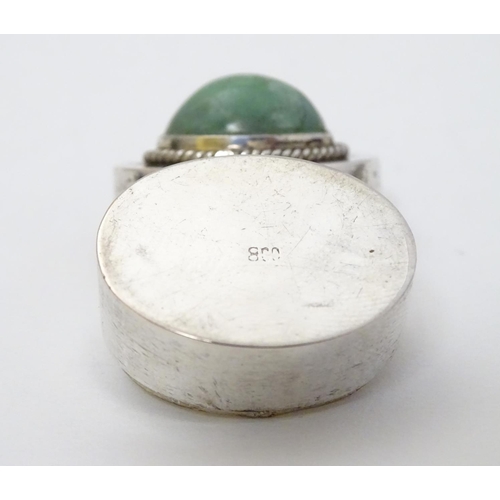 216 - A white metal pill box of oval form with jade cabochon to lid. 1'' wide