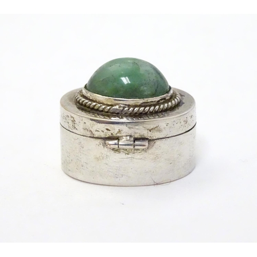 216 - A white metal pill box of oval form with jade cabochon to lid. 1'' wide