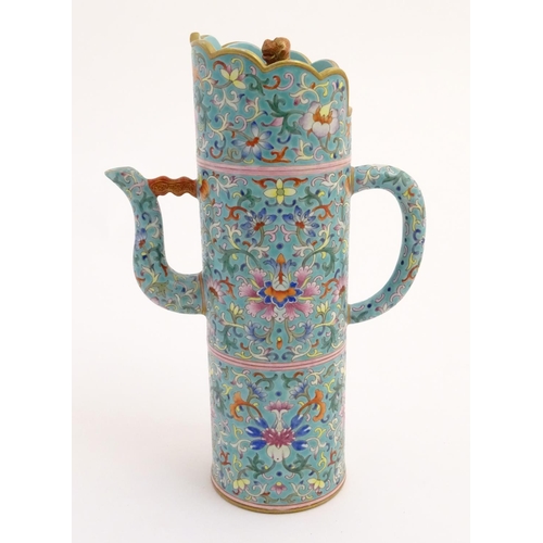 22 - A Chinese famille rose, Tibetan style tubular lidded wine ewer with a scrolling lotus design on a tu... 