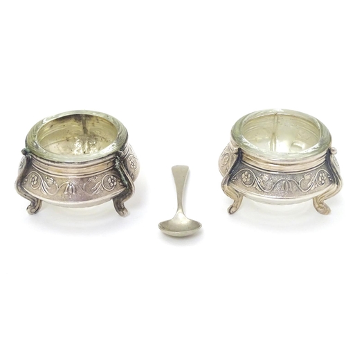 242 - A pair of Continental white metal salts with floral scroll decoration and clear glass liners. approx... 