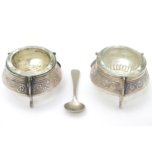 242 - A pair of Continental white metal salts with floral scroll decoration and clear glass liners. approx... 