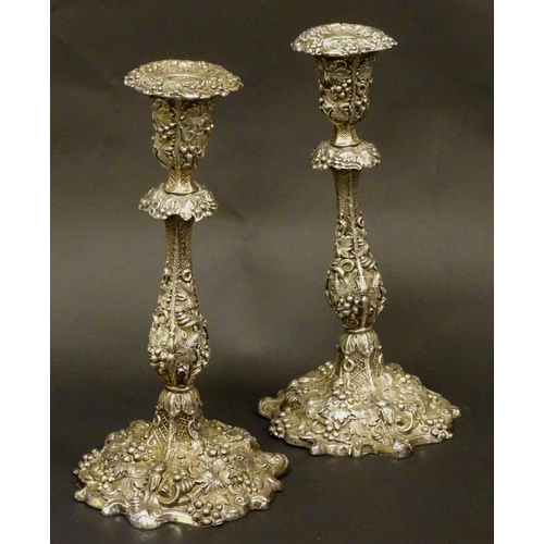 267 - A pair of silver plate candlesticks with profuse fruiting vine decoration. 10 1/4'' high