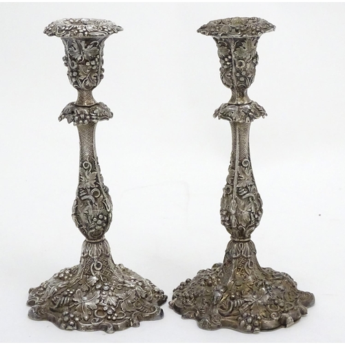 267 - A pair of silver plate candlesticks with profuse fruiting vine decoration. 10 1/4'' high