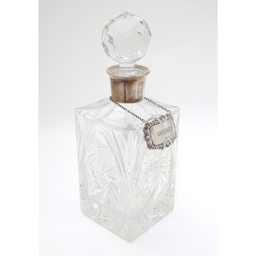 277 - A cut lead crystal decanter of squared form with silver collar and with silver wine label / decanter... 