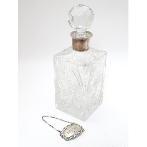 277 - A cut lead crystal decanter of squared form with silver collar and with silver wine label / decanter... 