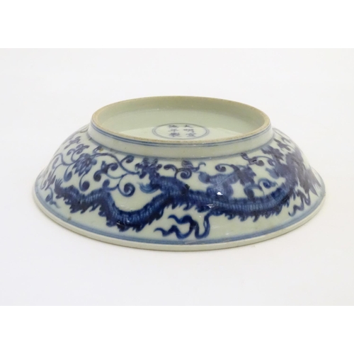 28 - A Chinese blue and white dish decorated with dragons, and scrolling flowers. Character marks to base... 