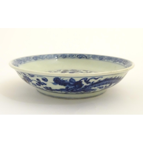 28 - A Chinese blue and white dish decorated with dragons, and scrolling flowers. Character marks to base... 