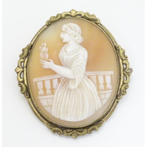 296 - A 19thC shell carved cameo brooch depicting a lady on  a terrace holding a flower. In gilt metal mou... 