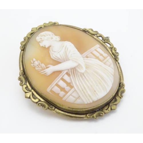 296 - A 19thC shell carved cameo brooch depicting a lady on  a terrace holding a flower. In gilt metal mou... 