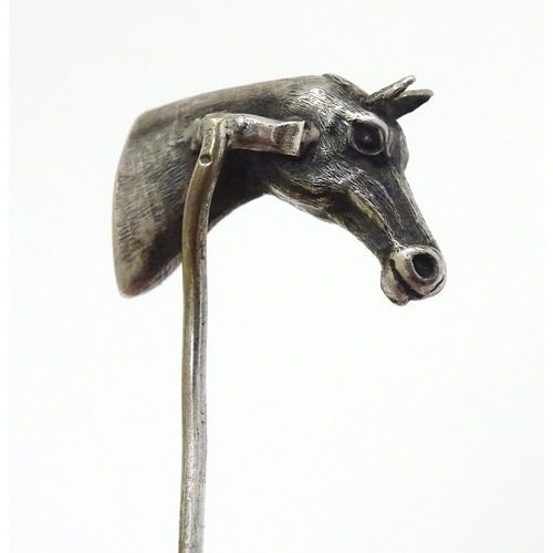 301 - A white metal stick pin surmounted by a horses head. Approx 3'' long overall