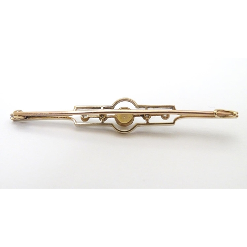 302 - An Art Deco gold brooch set with central pearl flanked by diamonds.   2 1/4'' wide