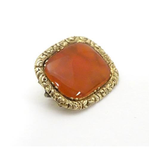 303 - A 19thC brooch set with central carnelian within an engraved yellow metal mount. 3/4'' wide