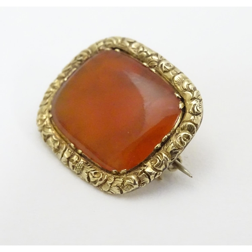 303 - A 19thC brooch set with central carnelian within an engraved yellow metal mount. 3/4'' wide