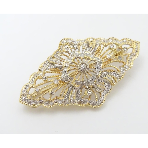 305 - A 18ct gold brooch set with a profusion of diamonds. 1 3/4'' wide