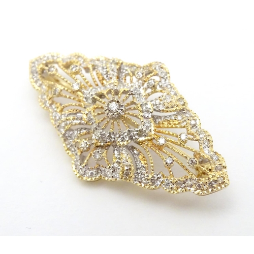 305 - A 18ct gold brooch set with a profusion of diamonds. 1 3/4'' wide