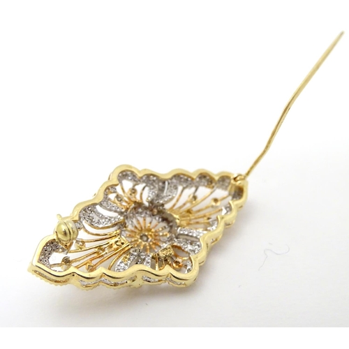 305 - A 18ct gold brooch set with a profusion of diamonds. 1 3/4'' wide