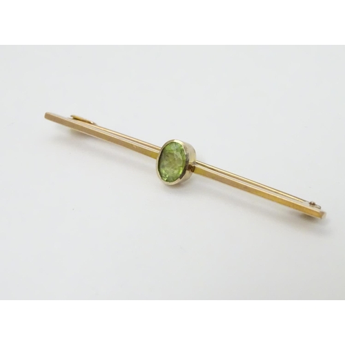 317 - A 9ct gold bar brooch set with oval peridot. 2'' long