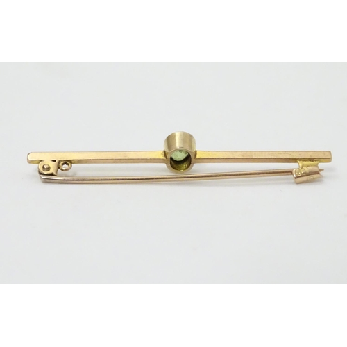 317 - A 9ct gold bar brooch set with oval peridot. 2'' long