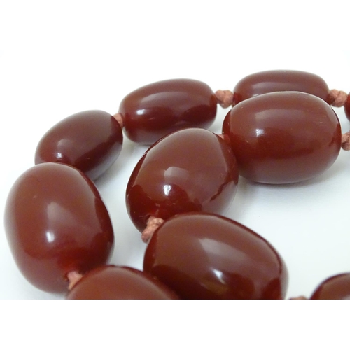 363 - A vintage necklace of graduated cherry amber coloured beads. The largest bead approx 1 1/8'' long