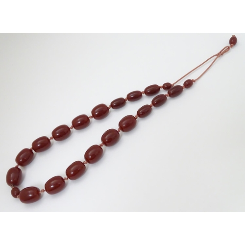 363 - A vintage necklace of graduated cherry amber coloured beads. The largest bead approx 1 1/8'' long