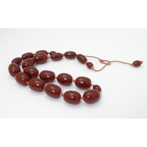 363 - A vintage necklace of graduated cherry amber coloured beads. The largest bead approx 1 1/8'' long