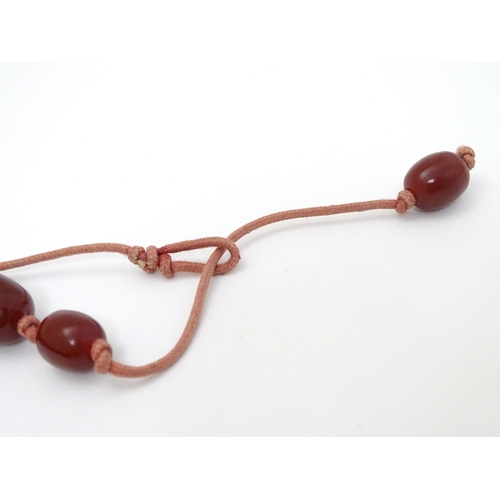 363 - A vintage necklace of graduated cherry amber coloured beads. The largest bead approx 1 1/8'' long