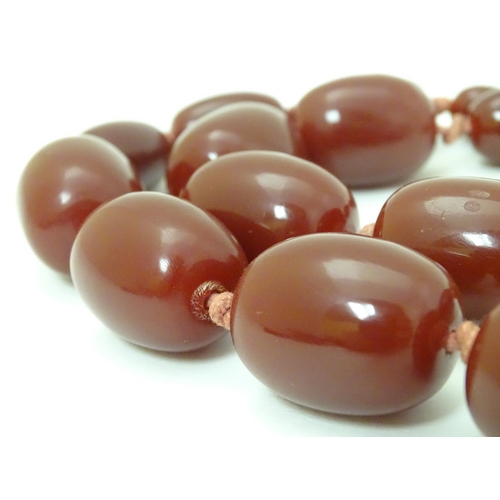 363 - A vintage necklace of graduated cherry amber coloured beads. The largest bead approx 1 1/8'' long