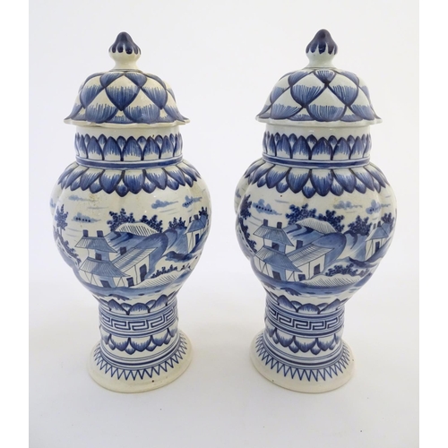 46 - Two blue and white ginger jars decorated with buildings in a landscape, and banded petal and geometr... 