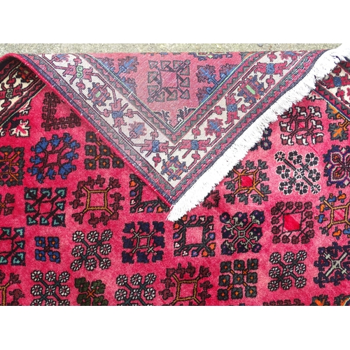 516 - Carpet / rug : a hand woven woollen rug with red central ground and 78 diamond shaped decorations to... 